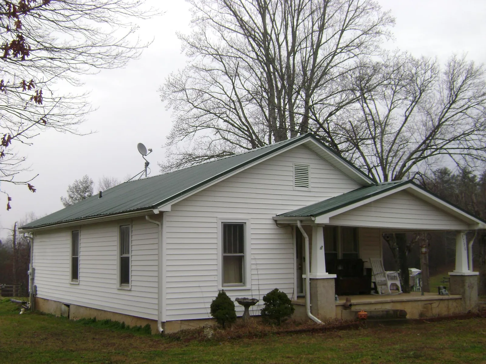 Green metal roof on a white bungalow with a side porch in Chapel Hill